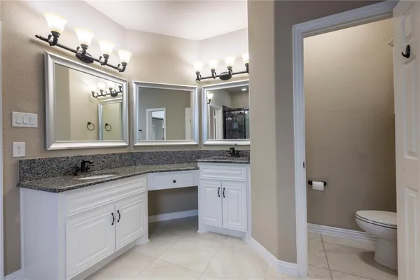 a spacious bathroom with a granite countertop sink a toilet and a mirror