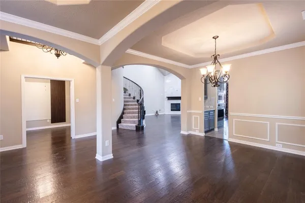 a view of a room with wooden floor chandelier and windows