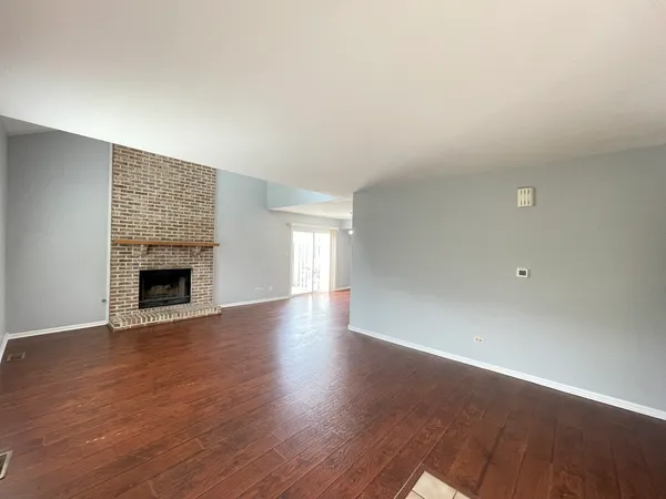 a view of an empty room with wooden floor and a fireplace