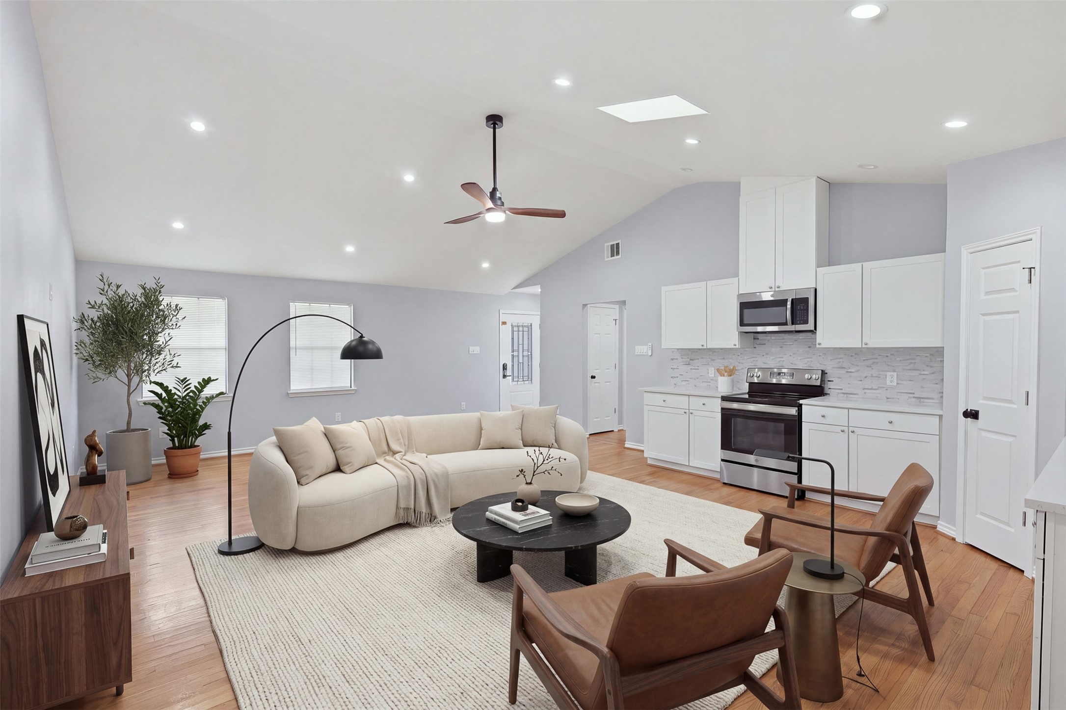 4926 Edfield Street Houston, TX 77033 - Photo 2 of 30 Spacious open-concept living area with vaulted ceilings, featuring a modern kitchen with stainless steel appliances and sleek white cabinetry.