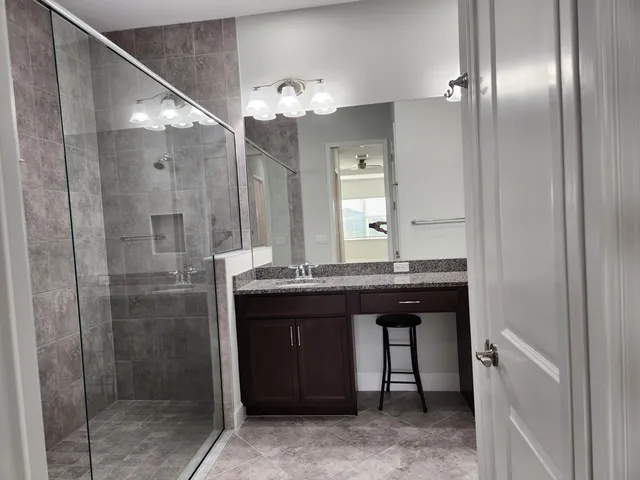 a bathroom with a granite countertop sink a large mirror and shower