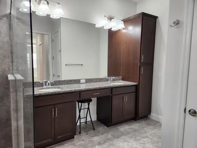 a bathroom with a granite countertop sink a mirror and shower