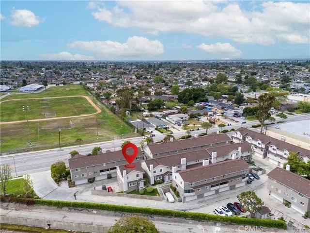 an aerial view of a city with lots of residential buildings ocean and mountain view in back