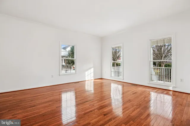 a view of an empty room with window and wooden floor