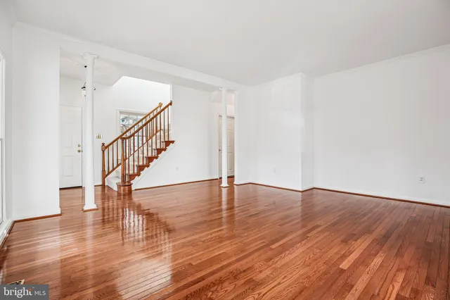 a view of an empty room with wooden floor and stairs