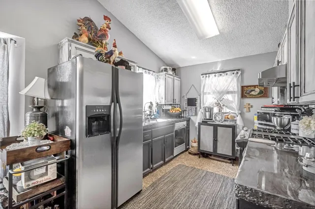 a kitchen with stainless steel appliances granite countertop a refrigerator a stove and a sink