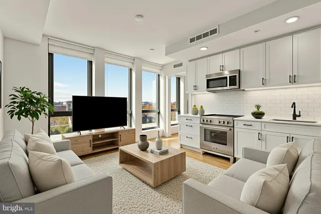 a living room with furniture a flat screen tv and kitchen view