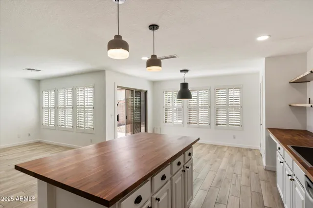 a view of an empty room with a kitchen and wooden floor