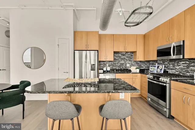 a kitchen with stainless steel appliances granite countertop a stove a sink a dining table and chairs with wooden floor