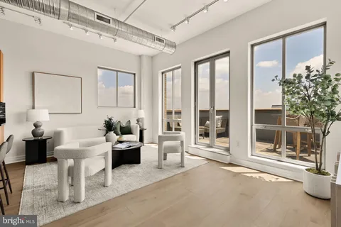 a living room with furniture a large window and potted plants