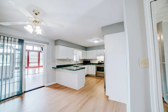 a kitchen with stainless steel appliances granite countertop a refrigerator a sink dishwasher a stove and white cabinets with wooden floor