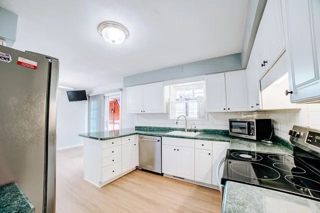 a kitchen with stainless steel appliances granite countertop a stove a sink and white cabinets