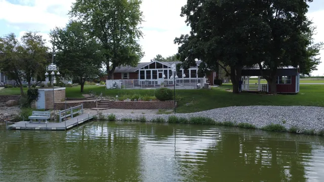 a view of house with swimming pool next to trees and covered with green space