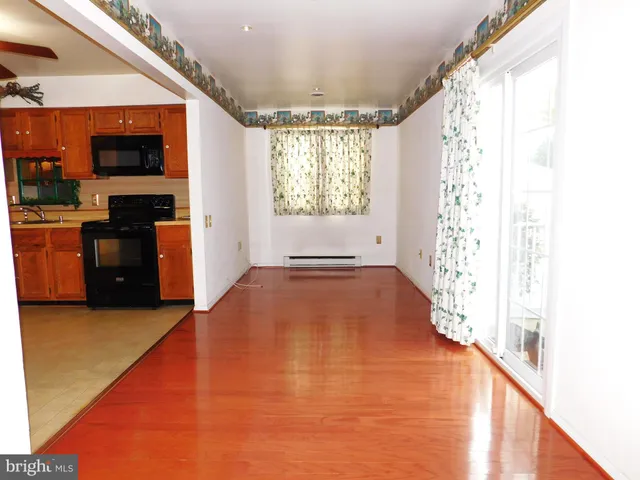 a view of an empty room with a window and kitchen view