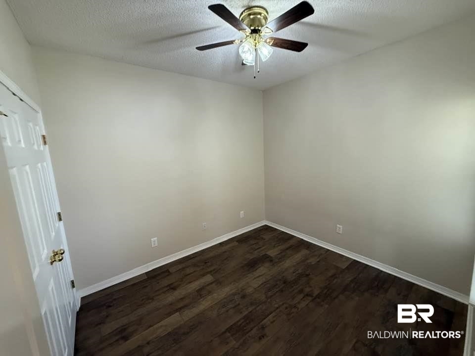 2651 South Juniper Street, Unit 401 Foley, AL 36535 - Photo 27 of 27 Empty room with a textured ceiling, a ceiling fan, dark wood-style floors, and baseboards