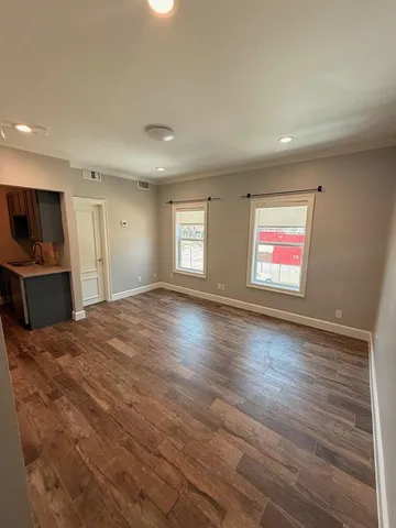 a view of empty room with wooden floor and windows