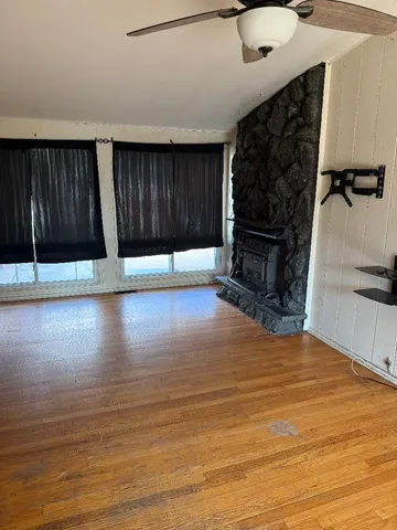 a view of a livingroom with wooden floor and a fireplace