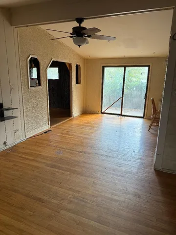 a view of an empty room with a window and wooden floor