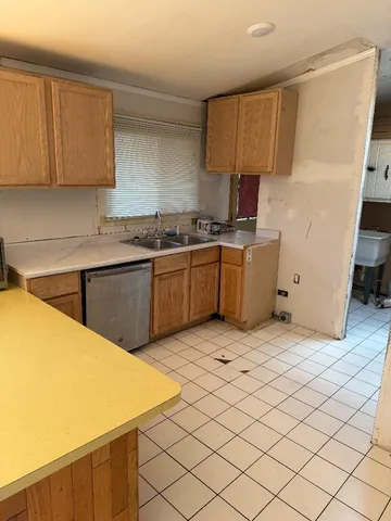 a kitchen with granite countertop a sink dishwasher stove top oven and cabinets