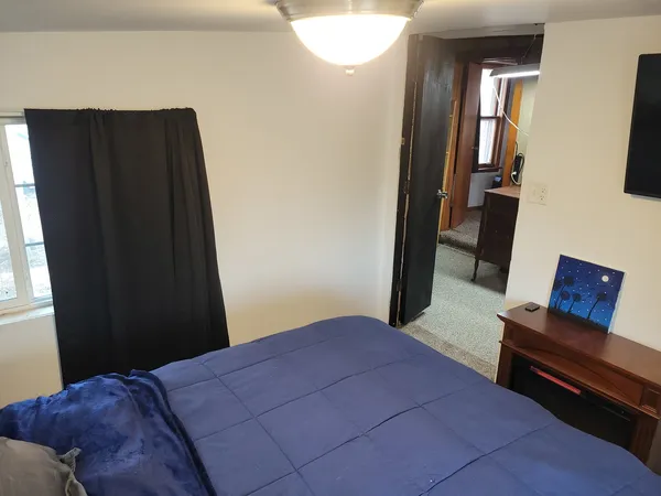 a bedroom with a bed and wooden floor