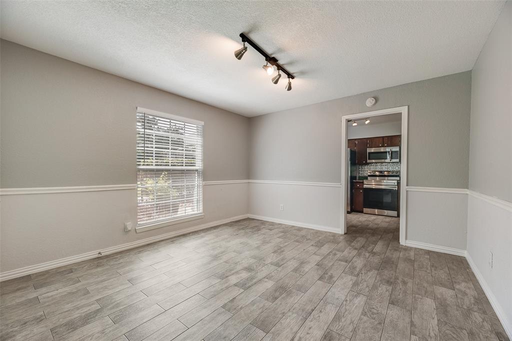 5109 Cedar Springs Road, Unit 105 Dallas, TX 75235 - Photo 6 of 16 Spacious room featuring wood-finish flooring, two-tone walls with chair rail molding, and a track lighting fixture