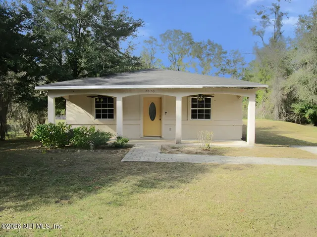 a front view of house with yard and trees in the background