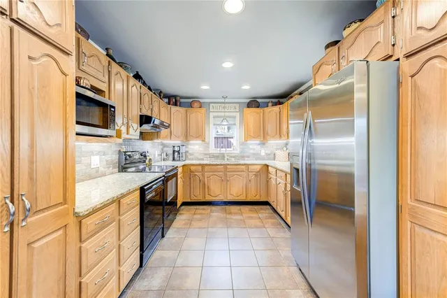 a large kitchen with stainless steel appliances kitchen island granite countertop a refrigerator and a sink