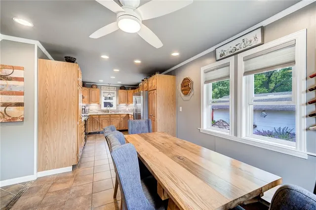 a large kitchen with kitchen island a large window cabinets a sink and stainless steel appliances