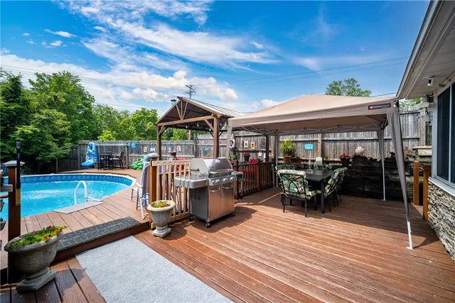 a view of a patio with dining table and chairs under an umbrella with wooden floor