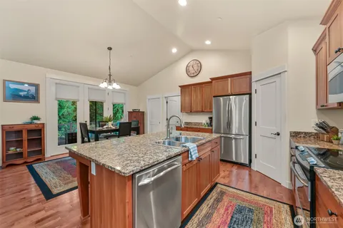 a kitchen with stainless steel appliances granite countertop a stove refrigerator and a wooden floor