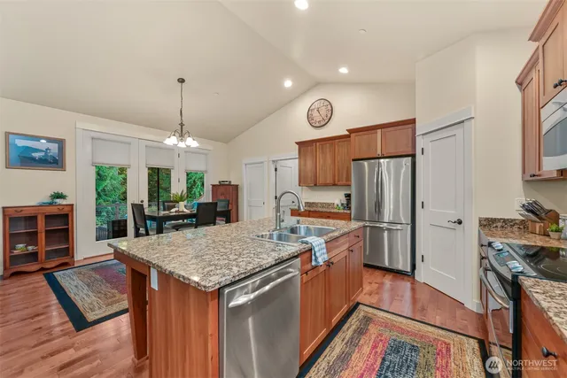 a kitchen with stainless steel appliances granite countertop a stove refrigerator and a wooden floor