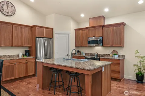 a kitchen with stainless steel appliances granite countertop a stove a sink dishwasher and a refrigerator with wooden cabinets
