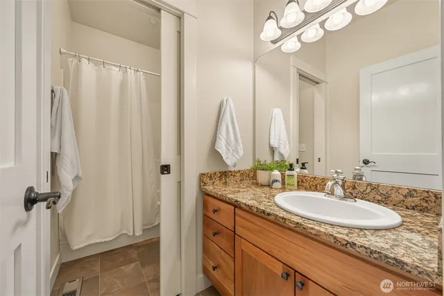a bathroom with a granite countertop sink a mirror and a shower
