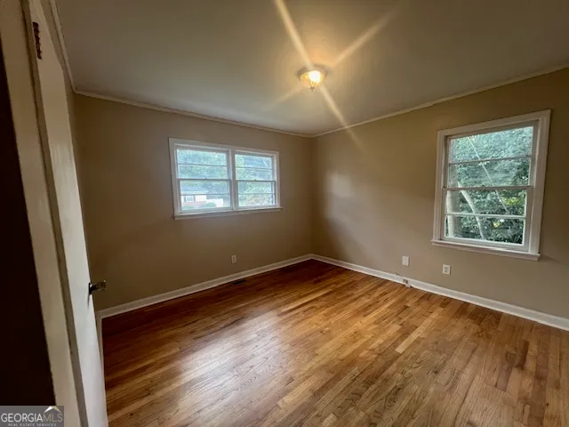 a view of an empty room with wooden floor and a window