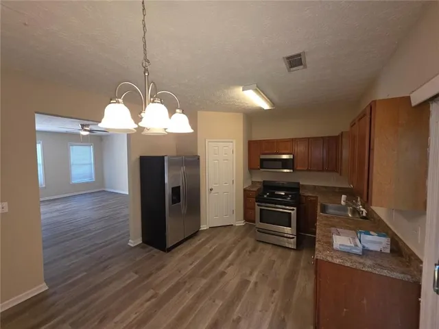 a kitchen with a refrigerator a stove and a wooden floor