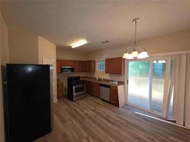 a kitchen with stainless steel appliances granite countertop a refrigerator a stove a microwave and a view of living room