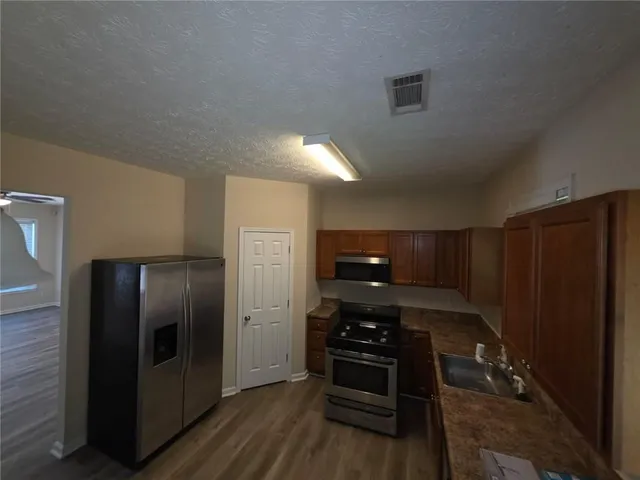 a kitchen with stainless steel appliances granite countertop a refrigerator and a stove top oven