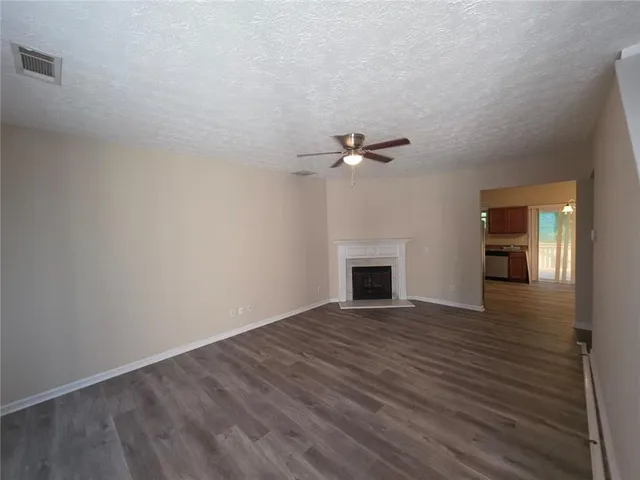 a view of an empty room with wooden floor and a fireplace