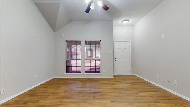 an empty room with chandelier fan and windows