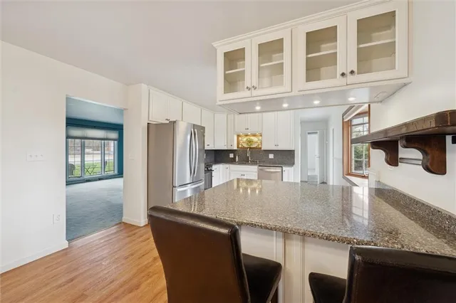 a kitchen with granite countertop a oven a refrigerator a sink and dishwasher with wooden floor