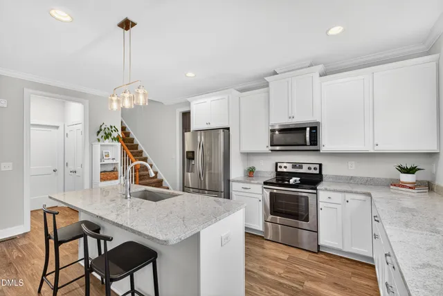 a kitchen with stainless steel appliances granite countertop a stove a sink dishwasher a refrigerator white cabinets and wooden floor