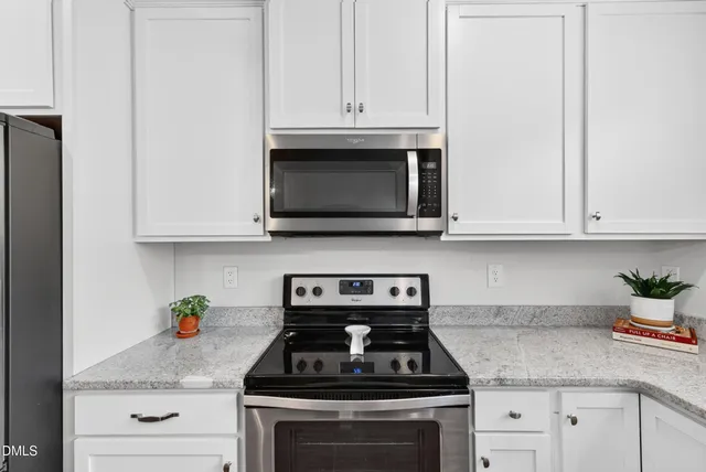 a kitchen with stainless steel appliances granite countertop white cabinets and a stove top oven
