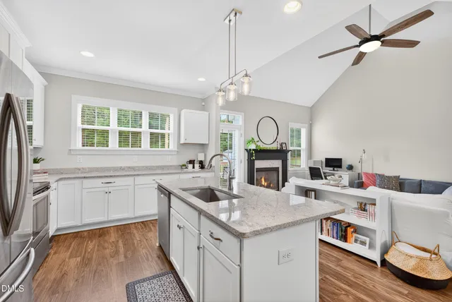a kitchen with granite countertop a sink cabinets stainless steel appliances and a large window