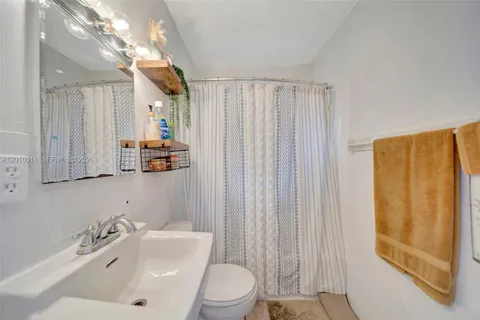 a bathroom with a sink a toilet and shower curtain