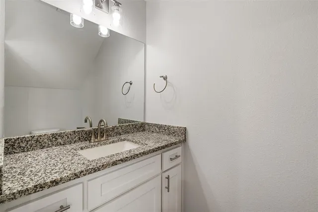 a bathroom with a granite countertop sink and a mirror