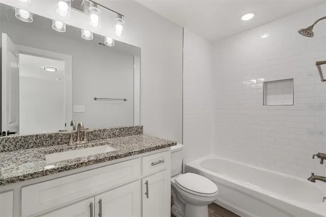 a bathroom with a granite countertop sink a toilet and bathtub