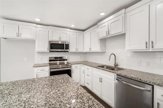 a kitchen with stainless steel appliances granite countertop a sink stove oven and white cabinets