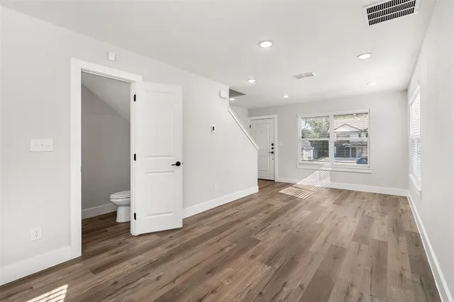 a view of empty room with wooden floor and window
