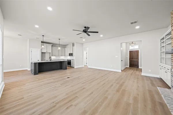 a view of kitchen and empty room with wooden floor