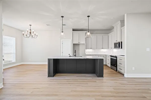 a kitchen with stainless steel appliances granite countertop a sink a stove and a wooden floors